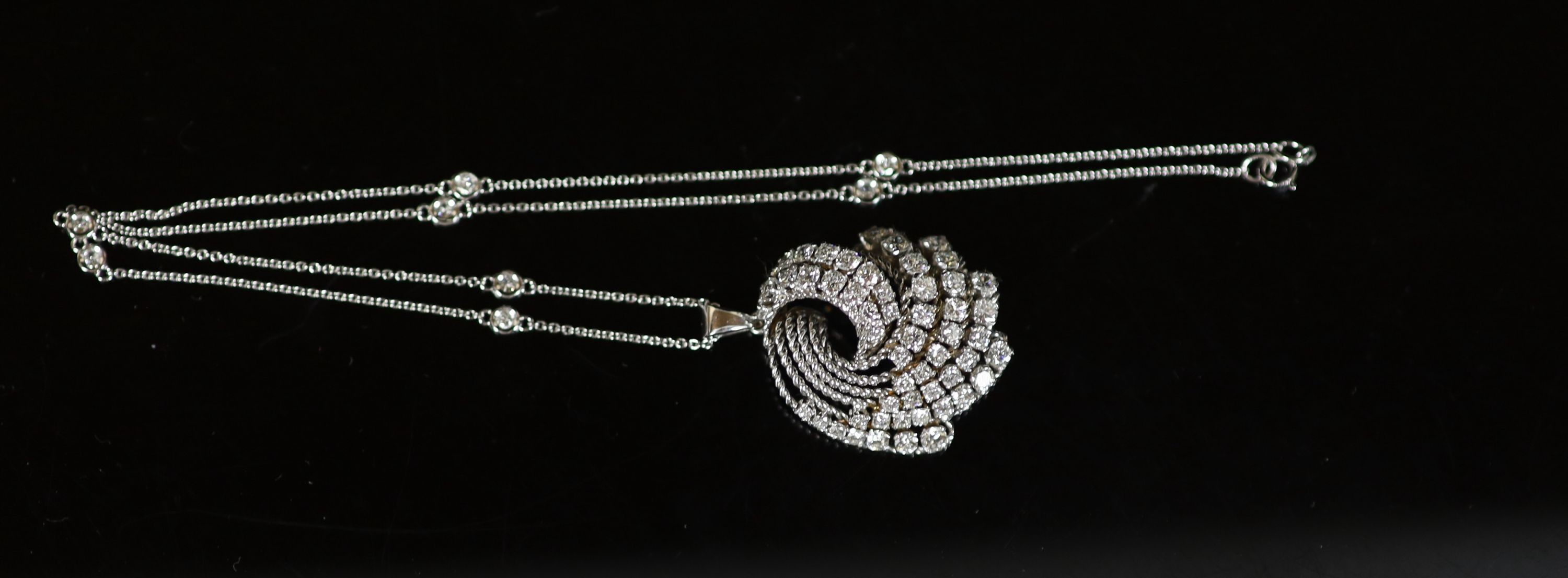 A modern white gold and graduated diamond set fan shaped scroll pendant, on a eight stone diamond set 18ct white gold chain